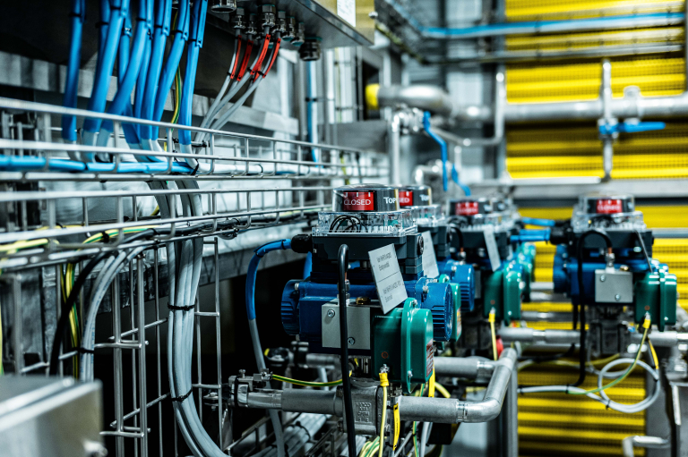 Automatiska ventiler med lägesindikatorer och kablage på kabelstegar i en industrimiljö