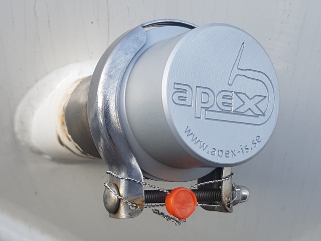 Ett täcklock i metall med Apex IS logotyp graverat